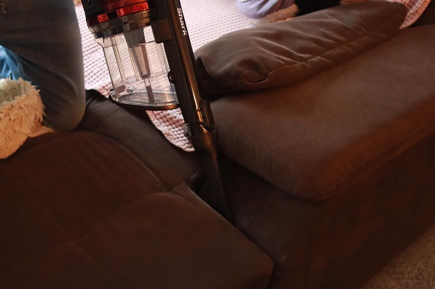 Shark Anti Hair Wrap Flexology IZ201UK is seen cleaning upholstered furniture. 